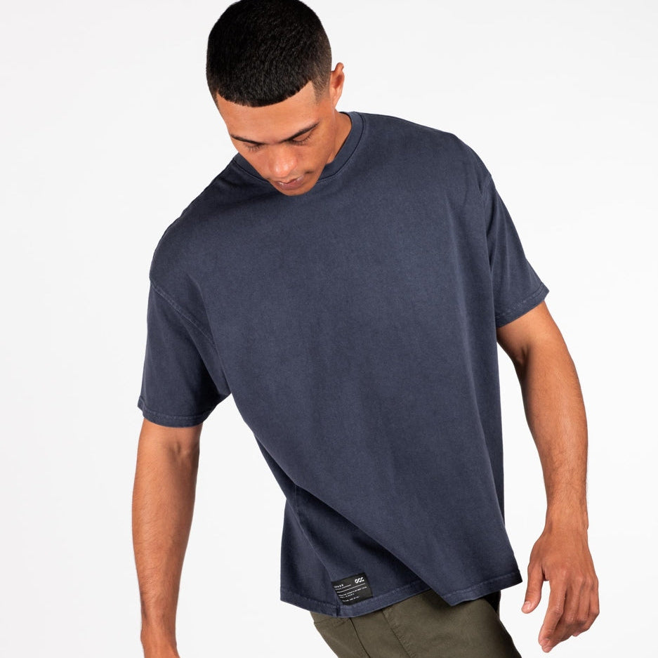 Man wearing a navy blue t-shirt and green cargo pants on a white background